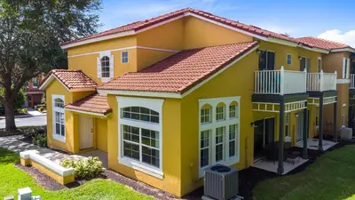 a large yellow house with a yard at Disney Area 4 bed/ 3.5 Bathroom Emerald Island in Kissimmee