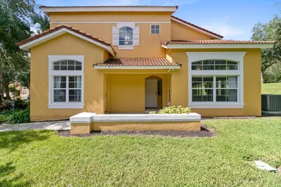 a yellow house with a lawn in front of it at Disney Area 4 bed/ 3.5 Bathroom Emerald Island in Kissimmee
