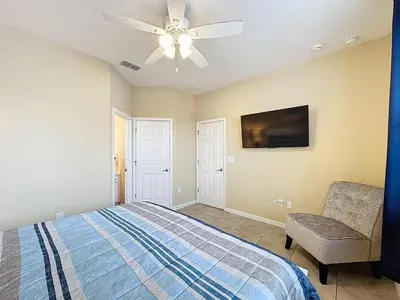 a bedroom with a bed and a ceiling fan and a chair at Veranda Home, 8br, 6 en-suites, Lake View,POOL/SPA in Kissimmee