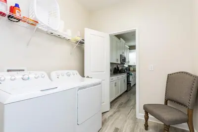 a white laundry room with a washer and a chair at Five bedroom home is ideal for an elegant vacation in Kissimmee