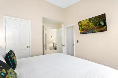 a white bedroom with a bed and a tv on the wall at South Facing Pool 4 Bedroom 3 Bath Villa in Kissimmee