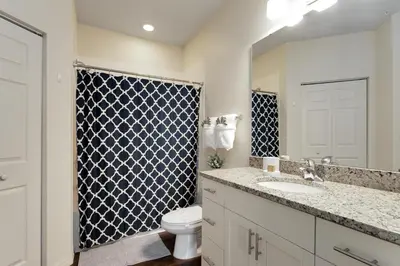 a bathroom with a toilet and a sink and a mirror at Lucaya Village Resort - 4 Bed 3 Bath Townhouse in Kissimmee