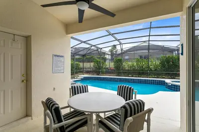 a patio with a table and chairs and a pool at Amazing Disney Dream Getaway in Windsor Palms! in Kissimmee