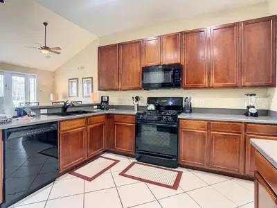 a kitchen with wooden cabinets and black appliances at Fantastic 7 Bed 6 Bath in Prestigious Gated Comm. in Orlando