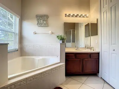 a bathroom with a tub and a sink and a mirror at Fantastic 7 Bed 6 Bath in Prestigious Gated Comm. in Orlando