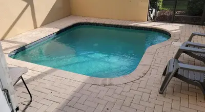 a small swimming pool with two chairs and a table at Three BR * 2 Miles to Disney, pool, free WiFi in Orlando