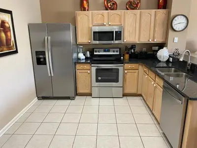 a kitchen with stainless steel appliances and wooden cabinets at Three BR * 2 Miles to Disney, pool, free WiFi in Orlando