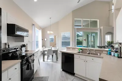 a kitchen with white cabinets and a dining room at Amazing 6 Bed Disney Dream Getaway in Windsor Palm in Kissimmee