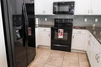 a kitchen with black appliances and white cabinets at Amazing 4 bedroom house near Disney in Kissimmee