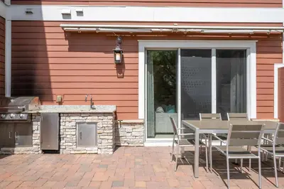 a patio with a table and a grill next to a house at 5 Min to Disney Dream 5 Suites Villa in Orlando