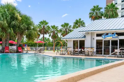 a pool at a resort with tables and chairs at Orlando International Drive North Hotel in Orlando