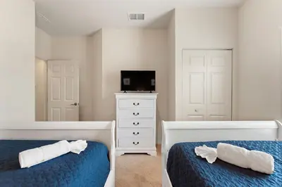a bedroom with two beds and a tv and a dresser at Lucky Find Lucaya Resort By Shine Villas 713 in Kissimmee