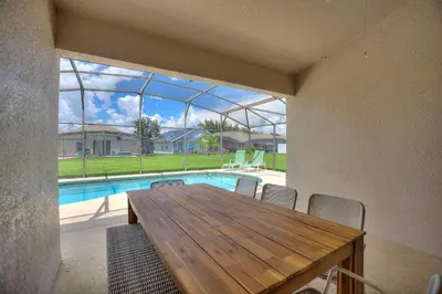 a dining room with a table and a swimming pool at Gilded Parasol By Shine Villas Remington Golf 420 in Kissimmee
