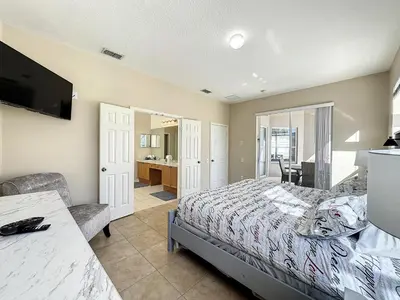 a bedroom with a bed and a television and a desk at Luxury 6BD 3.5BA Pool Home in Windsor Palms Resort in Kissimmee