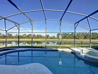 a swimming pool in a tent with a view of a lake at Emerald Island 4 bed mins to Disney in Kissimmee