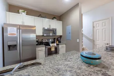 a kitchen with a stainless steel refrigerator and a counter top at Enjoy a Cozy 3 BR/Clubhouse/Near Disney and more in Kissimmee