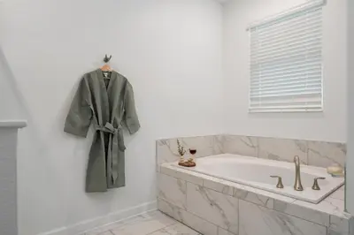 a robe hanging on a wall next to a bath tub at Luxury 9BR Gem- Heated Pool, Theater & Theme Rooms in Kissimmee