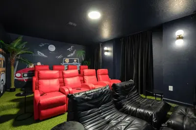 a room with a red sofa and leather chairs at Luxury 9BR Gem- Heated Pool, Theater & Theme Rooms in Kissimmee