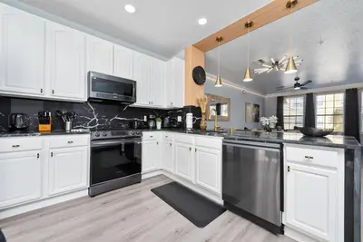 a kitchen with white cabinets and black appliances at Prime Location 3 Suites Townhome Near Universal in Orlando