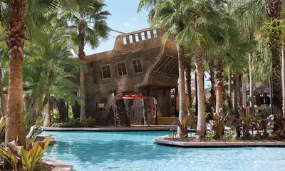a building with palm trees in front of a swimming pool at Bonnet Creek Resort 1 Bedroom 1 BA Deluxe Villa in Orlando