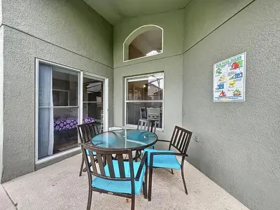 a table and chairs on a patio with a window at Four Bed Three Bath in a gated community with pool in Kissimmee