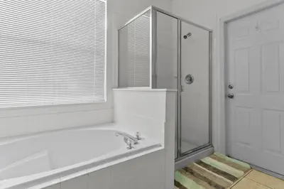a white bathroom with a tub and a shower at Three Bed Private Pool Villa just steps away from in Kissimmee