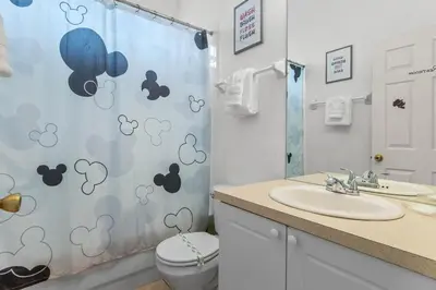 a bathroom with a shower curtain with a toilet and a sink at Three Bed Private Pool Villa just steps away from in Kissimmee