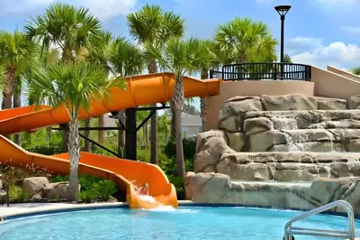 a water slide in a pool with palm trees at DLuxx Summer Vacation Home at Solterra Resort 7391 in Orlando