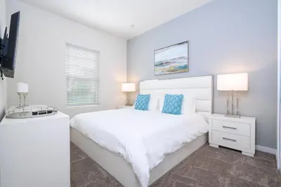 a white bedroom with a white bed with blue pillows at 5 min to Disney NEW Upscale 5 Suites Villa in Orlando