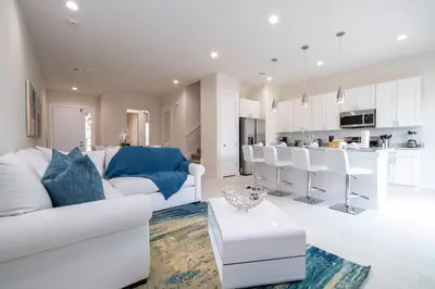 a living room with a white couch and a kitchen at 5 min to Disney NEW Upscale 5 Suites Villa in Orlando