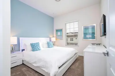 a white bedroom with a bed and a sink at 5 min to Disney NEW Upscale 5 Suites Villa in Orlando