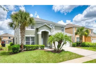 a large house with palm trees in front of it at The Minions Mansion 6br Resort Pool Home By Disney in Kissimmee