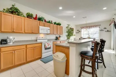 a kitchen with wooden cabinets and a counter top at 22 Mi to Disney Kissimmee Home with Pool and Hot Tub in Kissimmee