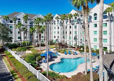 an apartment building with a pool and palm trees at Resort Family condo near Disney Pool view Free parks shuttle in Orlando