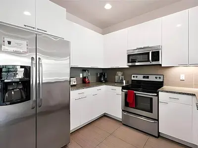 a kitchen with white cabinets and stainless steel appliances at MEMO Vacation House in Orlando