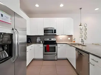 a kitchen with white cabinets and stainless steel appliances at MEMO Vacation House in Orlando