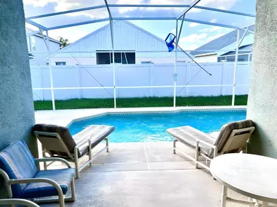 a swimming pool with two chairs and a table at Brittany - Perfect 3 BR Pool Home in Kissimmee