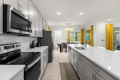 a large kitchen with white counter tops and appliances at 6 Bedrooms 5 Bathrooms Solara 1889 Tp in Orlando