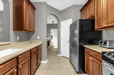 a kitchen with wooden cabinets and a black refrigerator at 3 Bedrooms 2 Bathrooms Vista Cay 4024-203 Bd in Orlando