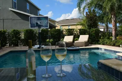 a bottle of wine and two wine glasses next to a swimming pool at Reunion Encore Resort Villa W/ Pool Spa Gameroom in Orlando