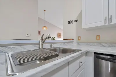 a kitchen with a stainless steel sink and white cabinets at Remodeled Retreat: Tranquil Resort Oasis Near Theme Parks in Kissimmee
