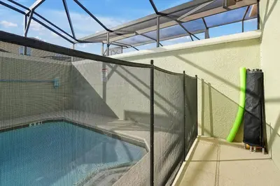 a swimming pool with a fence next to a building at Just renovated, private heated pool, resort access in Kissimmee