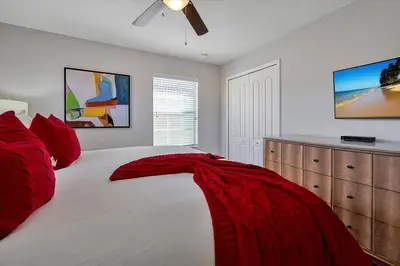 a bedroom with a large white bed with red pillows at Just renovated, private heated pool, resort access in Kissimmee