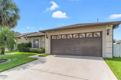 a house with a garage and a palm tree at 1589-IBRHAIM · Charming new 4bd in the heart of Kissimmee 1589 in Orlando