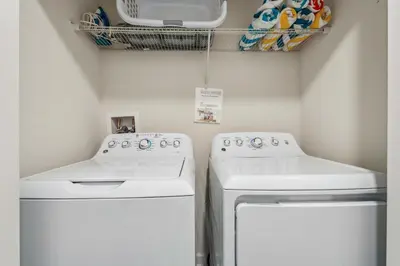 a laundry room with two white washers and a drying rack at 4BR Pool Home w Free Waterpark - 9 Min to Disney in Kissimmee