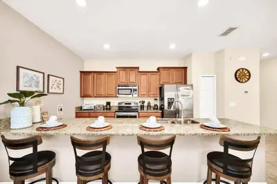 a kitchen with a large counter with chairs around it at Lovely Family Home - 10min to Disney - STL107 in Kissimmee