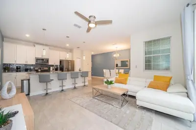 a living room with a white couch and a kitchen at 5013MO TOWNHOUSE 4 BEDROOMS & 3 BATHROOMS + POOL in Kissimmee