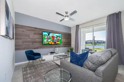a living room with a couch and a tv on a wall at 3131-102JJ STOREY LAKE, CONDO 2/2 LAKE VIEW in Kissimmee