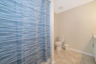 a bathroom with a toilet and a blue shower curtain at 3131-102JJ STOREY LAKE, CONDO 2/2 LAKE VIEW in Kissimmee