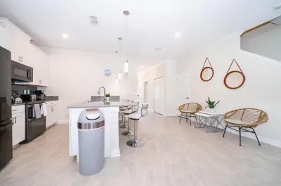 a white kitchen with a counter and chairs in it at 4301WB TOWNHOUSE 5 BEDROOMS & 4 BATHROOMS + POOL in Kissimmee